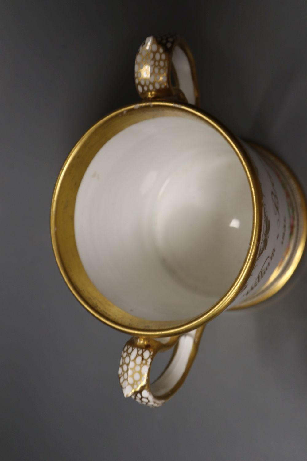 An English porcelain two handled mug lavishly painted with flowers, inscribed verso William Brown 1854, 14cm